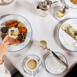 A lavish breakfast spread on a wooden table at Adare Manor, featuring pastries, fruits, juice, and a decorative floral centerpiece in a luxurious setting.