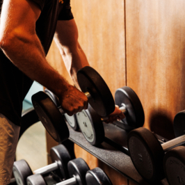 Guest in a hotel gym lifts a dumbbell from a rack, warm wood interior, focused workout at a 5-star luxury golf resort in Adare, County Limerick, Ireland