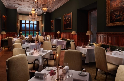 Elegant candlelit dining room at Adare Manor, 5-star Gothic Revival hotel in Adare, County Limerick, Ireland, set for fine dining.