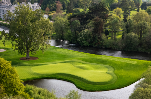 Aerial view of a luxurious estate, featuring a grand manor, lush gardens, and a sprawling golf course surrounded by dense greenery.