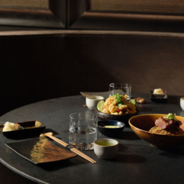 A beautifully plated dish with various culinary elements, including garnishes and sauces, artistically arranged on a textured ceramic plate on a wooden surface.
