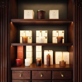 A luxurious scented candle in an ornate glass holder, adorned with a golden lid, sits on a polished wooden surface, exuding elegance and refinement against a soft-focused background.